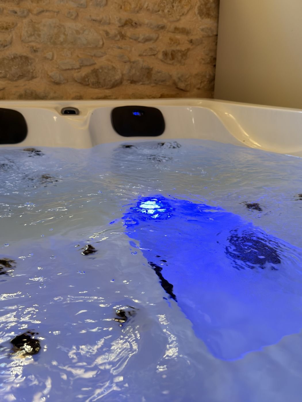 Le jacuzzi éclairé en bleu devant un mur en pierre